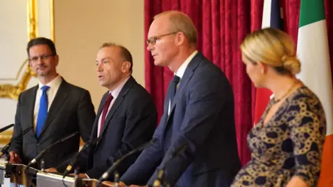 PA Media Chris Heaton-Harris (second left) and Simon Coveney (third left) spoke following a meeting in London