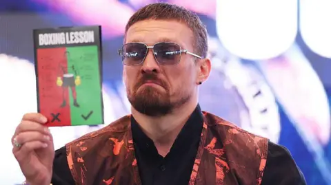 Oleksandr Usyk reading a 'boxing lesson' pamphlet 