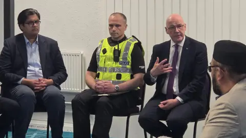 John Swinney, right, wearing a dark suit, speaking to members of the Muslim community at Broomhouse Mosque on Monday.