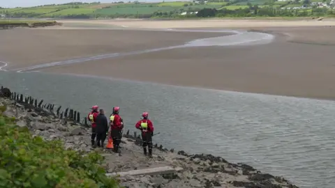 A view of the River Taw with emergency service teams stood at the side looking across the water.