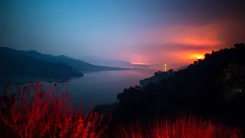 AFP The Thomas Fire burns a hillside behind Lake Casitas in Ventura, California on 8 December 2017