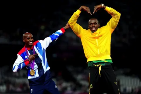 PA Media Mo Farah (left) doing Usain Bolt's signature victory pose as Bolt mimics Farah's "Mobot" on day 15 of the London 2012 Olympics