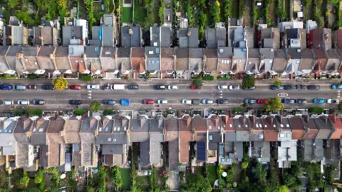 Getty Images An aerial shot of rows of terraced houses with back gardens. 