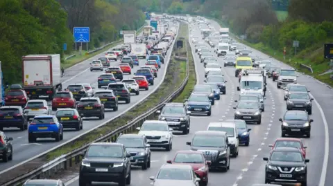 Cars queuing in both directions on the M5 motorway near Burnham-on-Sea in Somerset. &nbsp;There are trees either side of the motorway.