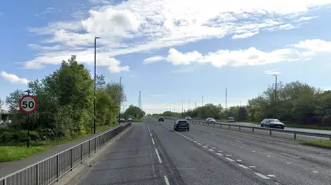 Google A dual carriageway with cars driving down it. There are 50mph speed limit signs.