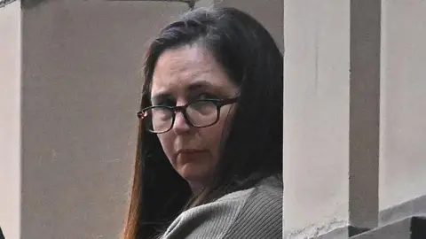 EPA Erin Patterson, wearing glasses, with long brown hair and looking at camera