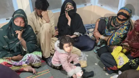 Getty Images, among a group of passengers, women and a small girl, wait at the Mach Railway station in Pakistan after releasing a kidnapped train