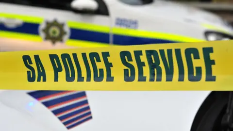 Getty Images A yellow police line written SA Police Service with a police vehicle in the background
