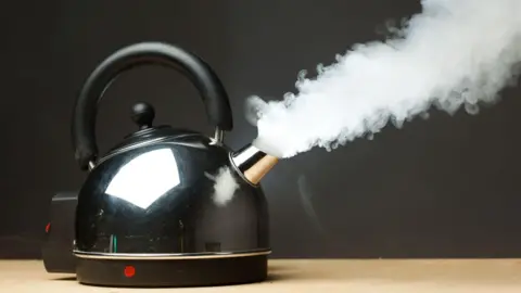 Getty Images Dense steam emerges from the spout of a silver kettle as it boils.