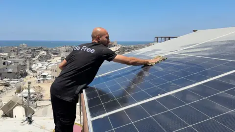 A man cleans the solar panels on top of the building where there is a co-working space for high-tech workers in Gaza City