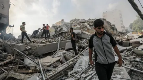 EPA Palestinians inspect the rubble of their homes near Watan Tower in Gaza City, 8 October 2023, following Israeli air strikes