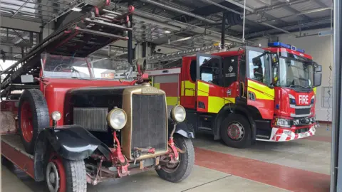National Emergency Services Museum An old fire engine next to a new one parked in a big garage.