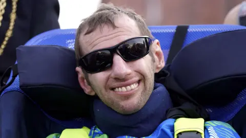 PA Media Rob Burrow wears black sunglasses and smiles