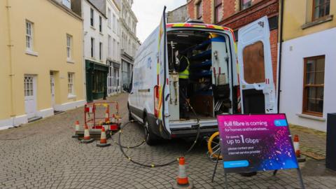 The back of an open van with a sign saying fibre and works going on