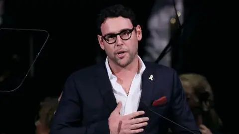 Getty Images Scooter Braun speaking at the Anti Defamation League's In Concert Against Hate at the Kennedy Center in the US last year. He is wearing black glasses, a white shirt and a navy suit.