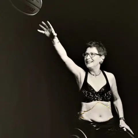 Carol Holliday/Ryan Davies A black and white image of Fiona Carey, photographed playing wheelchair basketball, with her scars filled in with gold leaf