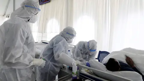 Reuters People in PPE treating a patient