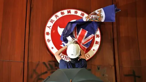 Getty Images Protester covering the Hong Kong emblem with a British colonial flag
