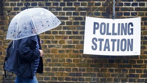 Man with umbrella outside a polling station