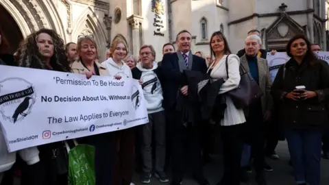 EPA/Shutterstock A group of people outside court. They are holding a banner.