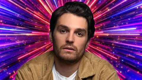 Lawrence Robb pictured in front of the pink and purple Strictly Come Dancing background