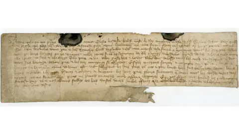 The family contract that dates back to 1397. There is old-fashioned handwriting and two large ink blots. The paper is tattered at the edges and yellow in colour from ageing.