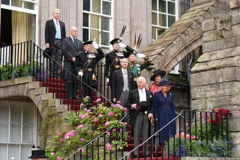 Getty Images King Charles III, followed by Queen Camilla, Princess Anne, Princess Royal and Prince Edward, Duke of Edinburgh, walks down the steps at the Palace of Holyroodhouse in Edinburgh as they arrive to attend the Garden Party. John Swinney, in Highland dress, is with them. They are all dressed in morning wear.