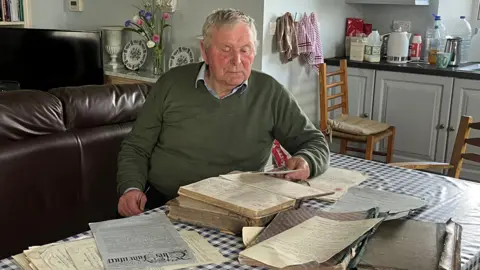 Tom Wall reading Christian Brother documents in his home 