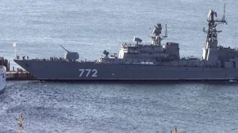 The Russian Neustrashimy frigate - a long, grey vessel with the number 772 printed on the side in white - in the water.