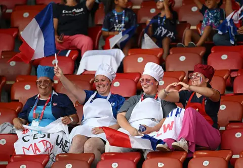 Getty Images Four women wearing aprons and chef hats cheer for France
