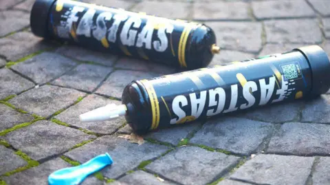 Getty Images Two discarded nitrous oxide cannisters on the ground alongside a deflated balloon.