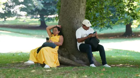 PA people sit in the shade beneath a tree