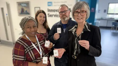 Shows three women and a man holding personal safety alarms