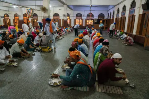 Getty Images Inside LANGAR Hall, the world's largest free and non-discriminatory dining hall located near the Golden Temple in Amritsar, India. Up to 100,000 people eat at LANGAR Hall during weekdays with that number doubling on weekends. Vegetarian food preparation, washing up and serving are all handled by volunteers and no plastics are used anywhere within the sprawling 5 story building. The operating costs are covered by visiting pilgrims, local businesses and overseas Punjabi donations. (Photo by Giles Clarke/Getty Images)