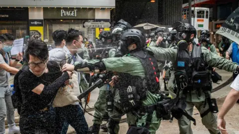 Getty Images Riot police pepper spray while clashing with a group of mediators during demonstrations against the draft bill.