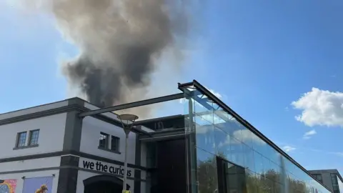 The 'We the Curious' museum on fire, seen from the outside with smoke coming from the building