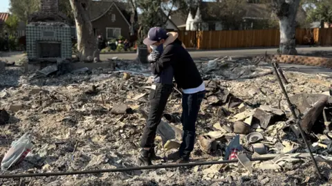 Harry Butler The couple hugging in the middle of the debris from the wildfires in LA. There is a house still standing in the background. 