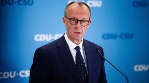 REX/Shutterstock Friedrich Merz, the conservative opposition leader, talked to the media in a suit and tie a day after the knife attack in Bavaria