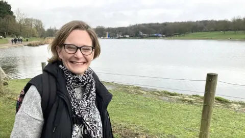 Amy Holmes/BBC Mel Cucos - "Stevenage Woman" - standing by a lake