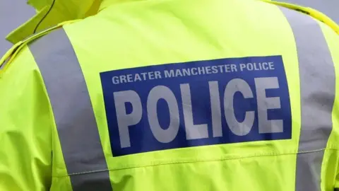 A high-vis Greater Manchester Police jacket with the force's name emblazoned on the back. 