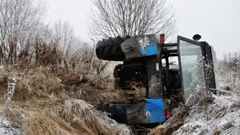 Getty Images A tractor on its side in a ditch