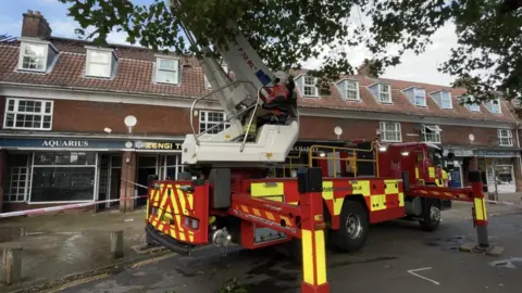 Robby West/BBC Fire engine next to parade of shops