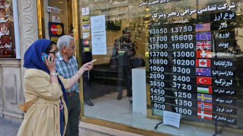 AFP People walk past a foreign exchange shop in Tehran, Iran (22 April 2019)