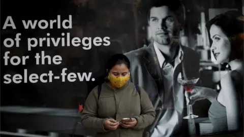 EPA An Indian commuter wears a protective mask as she waits next to a vaccination center in Kolkata, India, 03 February 2021.