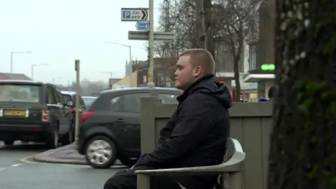 BBC Sam, 23, sitting on bench