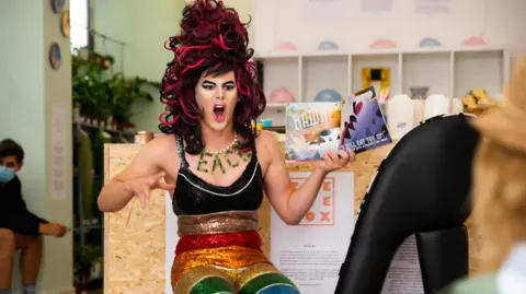 Drag queen reading book to children in library