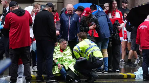 PA Media Emergency service workers and onlookers following the Liverpool parade car incident