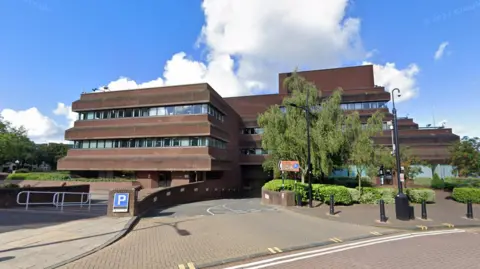 Google An angular three- storey red brick building 