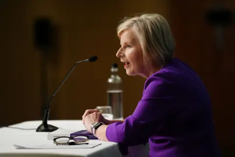 Jacob King/PA Wire Donna Ockenden, wearing purple, speaks into a microphone.