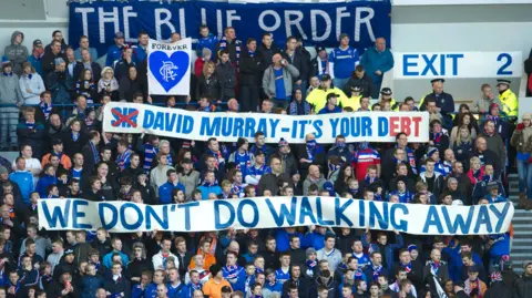 SNS Rangers fans in the stands with two signs. One reads "Sir David Murray - it's your debt" but with the word "sir" crossed out. The other reads "we don't do walking away".